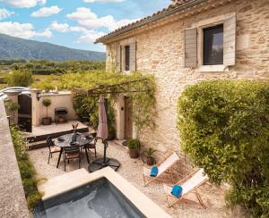 a patio with a table and chairs and a house at Le Mas des Sablières in Oppède