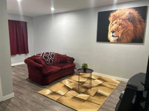 a living room with a red chair and a lion painting at Cute Highland Park Upper B Unit in Calgary