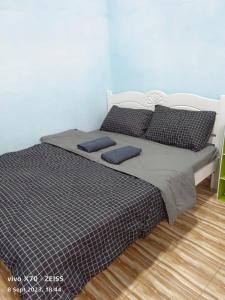 a bed with two pillows on it in a bedroom at D'DUSUN RAUDHAH HOMESTAY in Baling