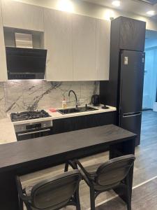 a kitchen with a counter with two chairs and a sink at Jikia Residence in Tbilisi City