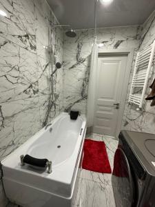 a white bath tub in a bathroom with marble walls at Jikia Residence in Tbilisi City +18 photos