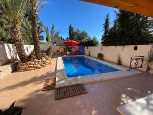 a swimming pool in a backyard with palm trees at Casita El Aljibe in Gebas