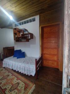 um quarto com uma cama e uma porta de madeira em Recanto da minha flor - Praia da Pinheira em Palhoça