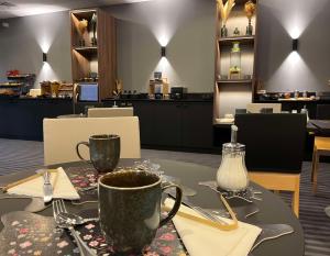 una mesa con una taza de café encima en Best Western Plus La Fayette Hotel et SPA, en Épinal