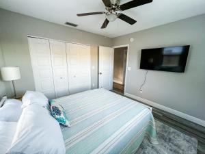 a bedroom with a bed with a ceiling fan and a flat screen tv at The Cottage in Dunedin