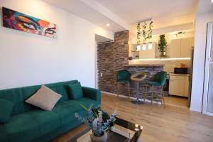 a living room with a green couch and a kitchen at Apartament Beauty Smarald by Cosmopolis in Ştefăneştii de Jos
