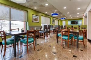 フェントンにあるDrury Inn & Suites St. Louis Fentonの木製のテーブルと椅子、緑の壁が備わるレストラン