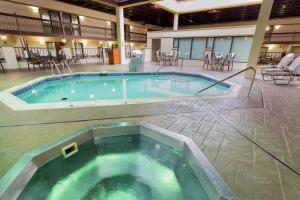 una gran piscina en un edificio con mesas y sillas en Pear Tree Inn St Louis Convention Center, en Saint Louis