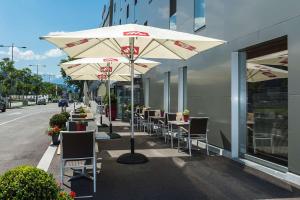 因斯布魯克的住宿－Tivoli Hotel Innsbruck，人行道上一排带遮阳伞的桌椅