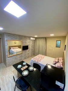 ein Schlafzimmer mit einem Bett und einem Tisch und einem Fernseher in der Unterkunft Pousada kanoas suites in São José da Coroa Grande