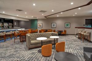 a waiting room with a couch and tables and chairs at DoubleTree by Hilton Lansing in Lansing