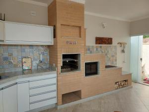 a kitchen with a brick wall with a fireplace at Alto Padrão! Vista linda! Churrasqueira! Hidro! in Poços de Caldas