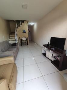 a living room with a couch and a television at Casa Duplex Arraial do Cabo 30 metros do Mar in Arraial do Cabo