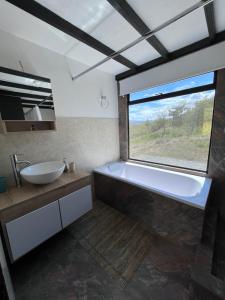 baño con bañera, lavabo y ventana en Villa Skape - Finca Villa Carolina en Villa de Leyva