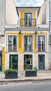 un bâtiment jaune et blanc avec des fenêtres sur une rue dans l'établissement VAGO Alcântara Suites, à Lisbonne