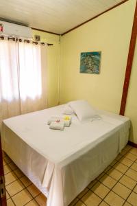 a bedroom with a large white bed with towels on it at Pousada do Romildo in Fernando de Noronha