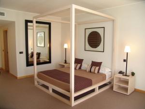 a bedroom with a canopy bed and a mirror at Miravillas Hotel in Praia de Mira