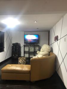 un ours en peluche assis sur un canapé devant une télévision dans l'établissement Departamento Amoblado, à Huaraz