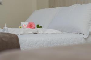 a white bed with a pink flower on top of it at Hotel Scoz in Pouso Redondo