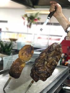two pieces of meat being fried on a grill at Hotel Scoz in Pouso Redondo