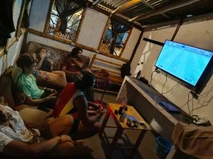 um grupo de pessoas sentadas numa sala de estar a ver televisão em Munay Backpacker Hostel em Montañita