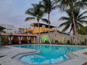 a swimming pool in front of a building with palm trees at Pousada Jardins in Santarém