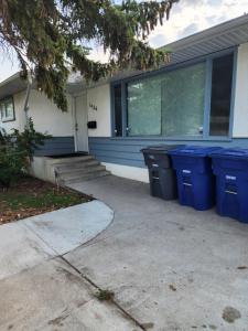 une maison avec des poubelles bleues devant elle dans l'établissement TheSunshine: Bright&Peaceful 2 Bdrm Character Home, à Saskatoon