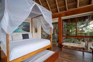 a bedroom with a canopy bed and a balcony at Xoot Kaana Villa Vista Laguna in Bacalar