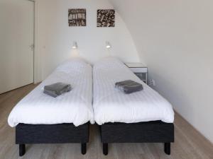 zwei Betten mit weißer Bettwäsche und zwei Taschen darauf in der Unterkunft Zeebaars in Egmond aan Zee