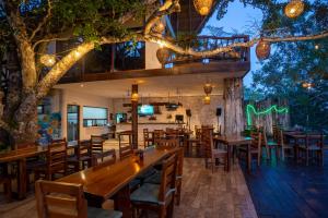 a restaurant with wooden tables and chairs and a tree at Xoot Kaana Villa Vista Laguna in Bacalar