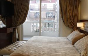 a bedroom with a bed and a large window at Alta Piazza –Casa di Appartamenti– in Buenos Aires