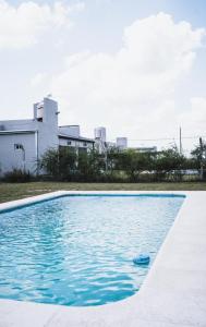 - une piscine d'eau bleue en face d'un bâtiment dans l'établissement Casa quinta con entorno rural, à Chacabuco