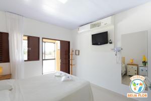 um quarto branco com uma cama e uma televisão em Pousada Beija-Flor em Chapada dos Guimarães