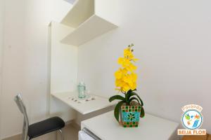 uma flor amarela num vaso sobre uma mesa branca em Pousada Beija-Flor em Chapada dos Guimarães