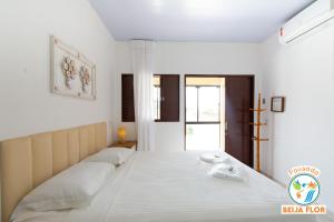 - une chambre avec un grand lit blanc et une fenêtre dans l'établissement Pousada Beija-Flor, à Chapada dos Guimarães