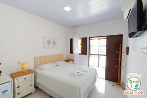 a bedroom with a bed and a tv and a window at Pousada Beija-Flor in Chapada dos Guimarães