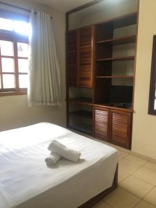 Schlafzimmer mit einem weißen Bett und einem TV in der Unterkunft Apartamento do Mário 128D in Porto Seguro