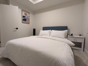 a bedroom with a large white bed with a blue headboard at Comfy 2BR condo in Seton, Southeast Calgary in Calgary