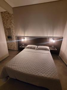 a bedroom with a large bed with two lights on it at Mimos Hospedagem in São Paulo