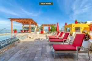 a patio with red chairs and a pool at Chic Studio w/Rooftop Pool - Ocean View - King Bed in Puerto Vallarta