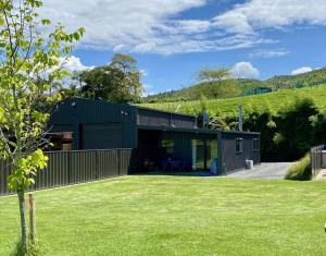 a green house with a green yard at Brightside Cosy Farmstay in Papamoa