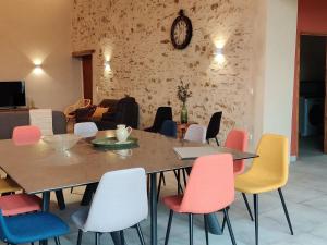 a dining room with a table and colorful chairs at Gîte rénové avec piscine intérieure, accessible PMR, en plein cœur du Bocage Vendéen. - FR-1-426-536 in Cheffois