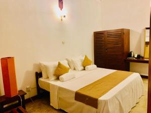 a bedroom with a large bed with yellow pillows at Salty Seahorse Mount Lavinia in Watumulla