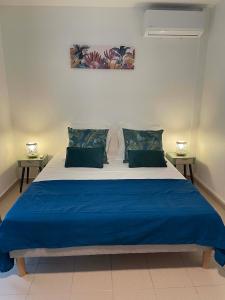 una camera da letto con un grande letto con lenzuola e cuscini blu di Appartement tout confort ! Au pied de la plage ! a Sainte-Anne