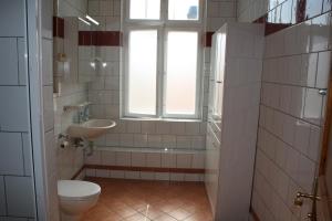 a bathroom with a toilet and a sink and a window at Pensionszimmer Unicat in Potsdam