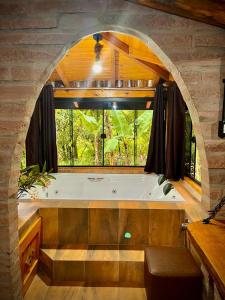 bañera grande en una habitación con ventana en Aldeia Pé da Serra Cabana Natureza, en Três Coroas