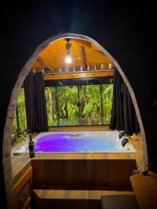 La salle de bains est pourvue d'une grande baignoire et d'une fenêtre. dans l'établissement Aldeia Pé da Serra Cabana Natureza, à Três Coroas