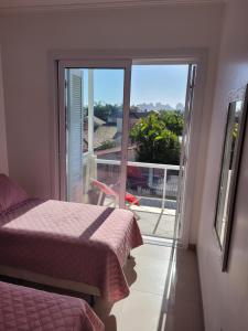 a bedroom with a bed and a window with a view at Apto 2 quartos - 250 m da praia de Atlântida in Xangri-lá