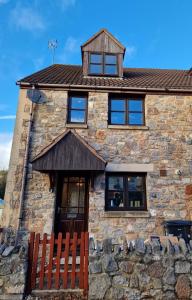 a stone house with a brown door and windows at Purdie Close Holiday Let in Cheddar