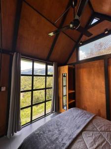 a bedroom with a bed and a large window at Casa Lanzo, montañas y lago in Macanal